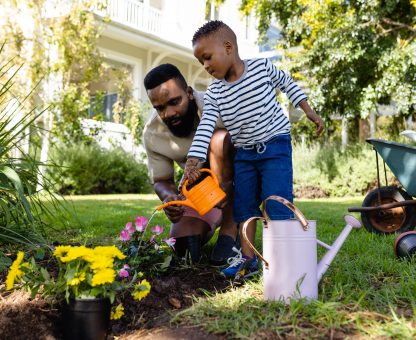 African,American,Father,With,Son,Watering,Flower,Pots,And,Plants